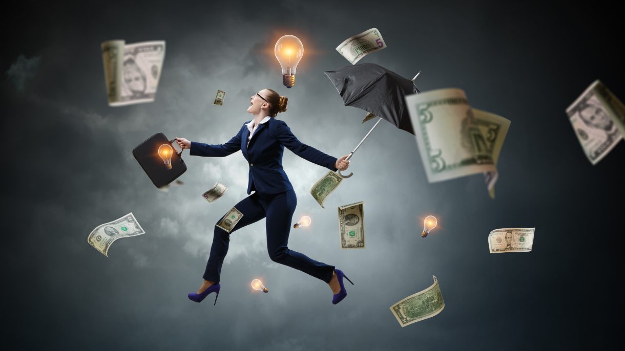 Entrepreneur in a suit walking under a storm of money and light bulbs, representing ideas.